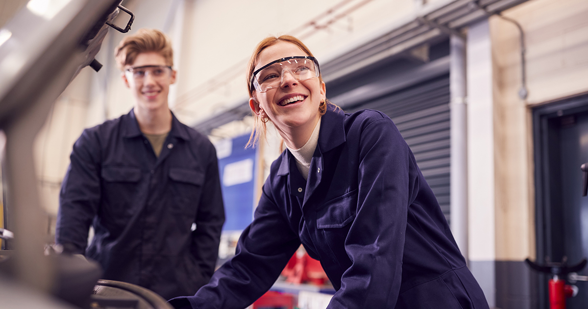 Young white woman and young white man learning automobile maintenance