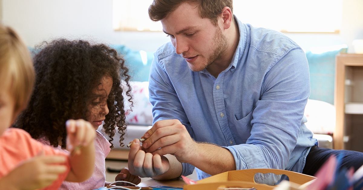 White male teacher helping young Black female student