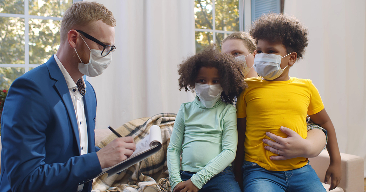 social worker with medical mask visits a family with kids