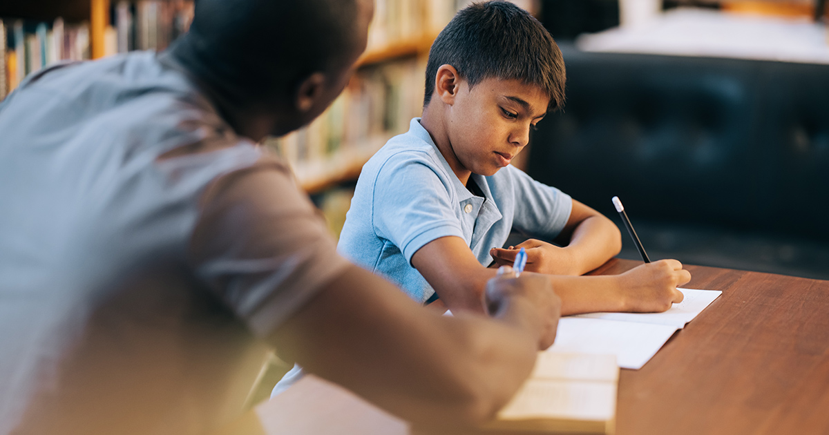 A man helps a schoolchild with a worksheet