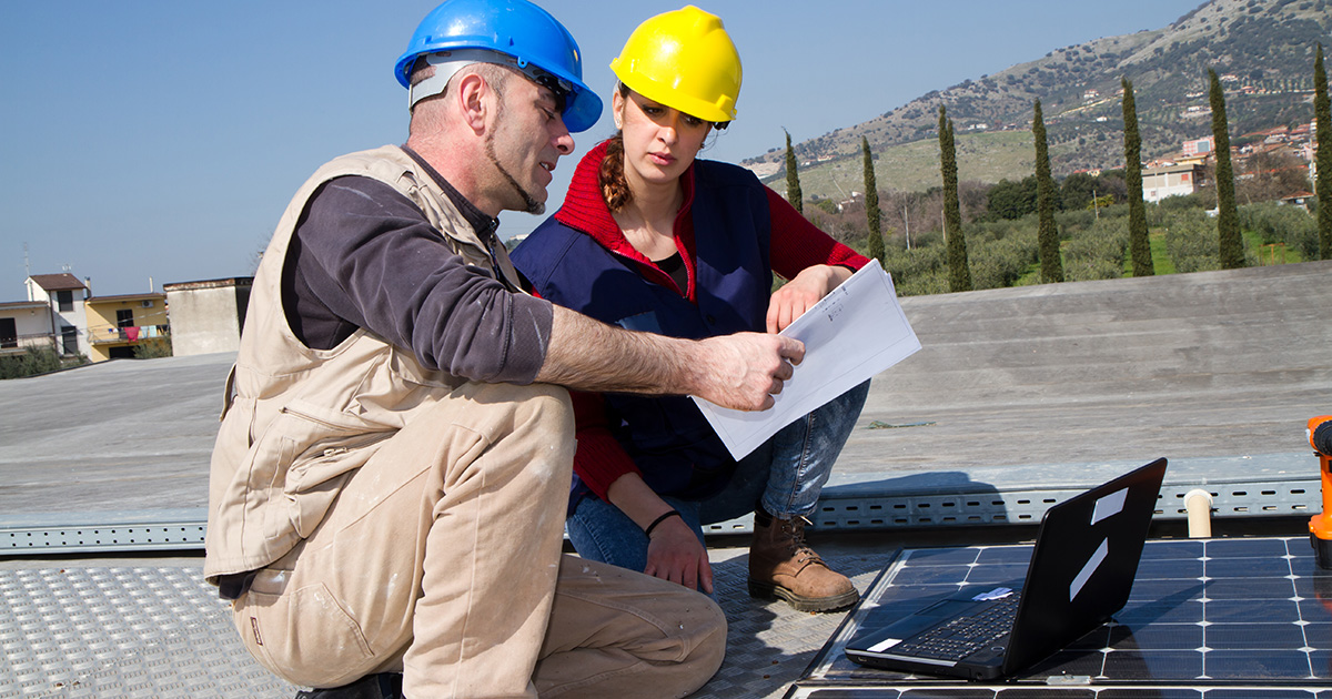 Older man instructing young women re solar system installation