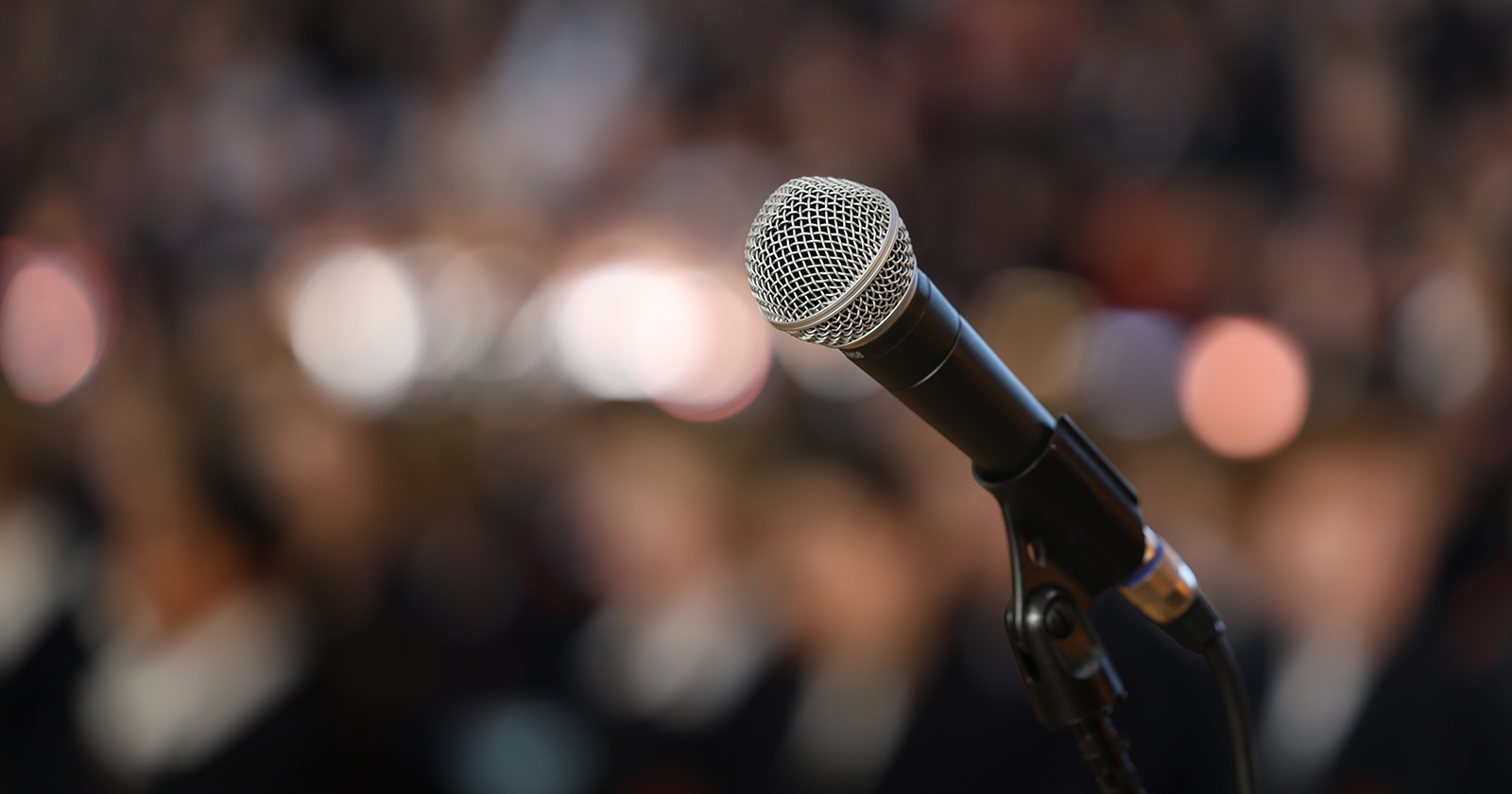 Close-up of microphone with blurred audience in background