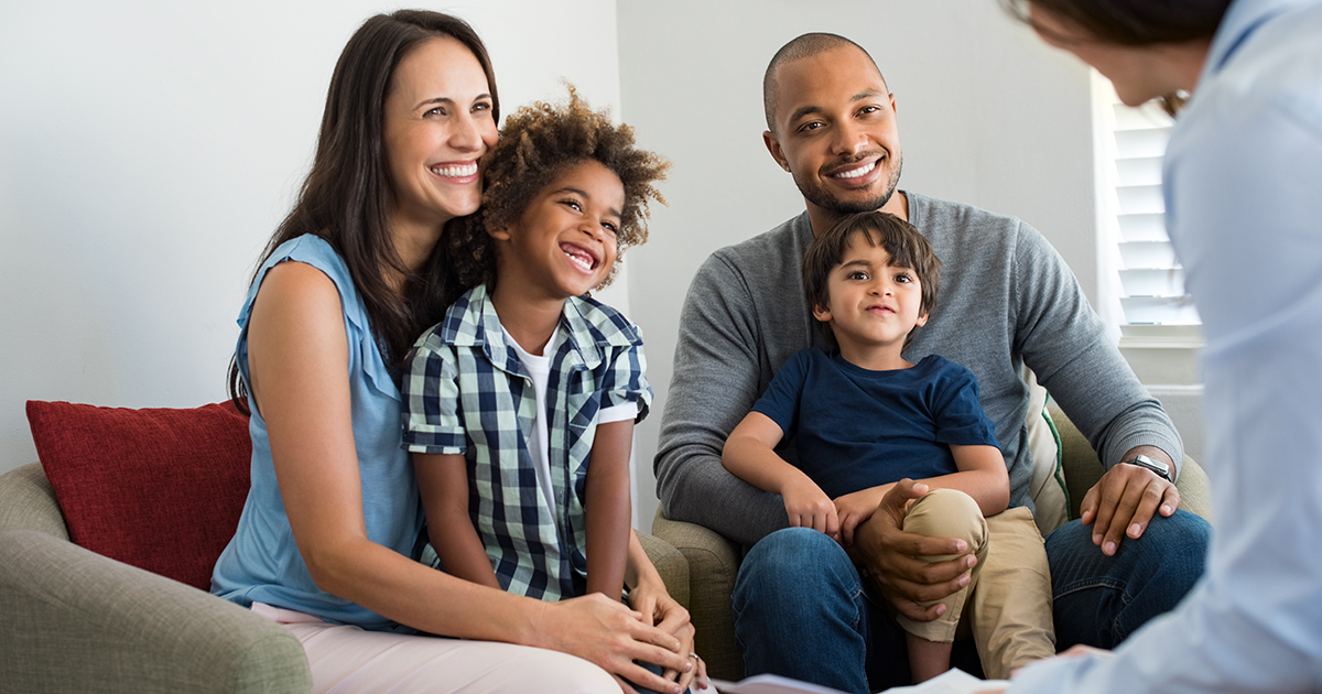 A family with two kids talking to a program staff