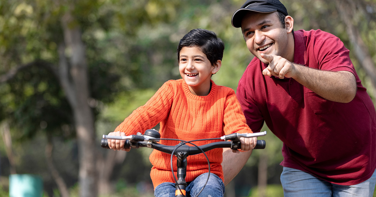 Father si teaching his son to ride a byke in the park