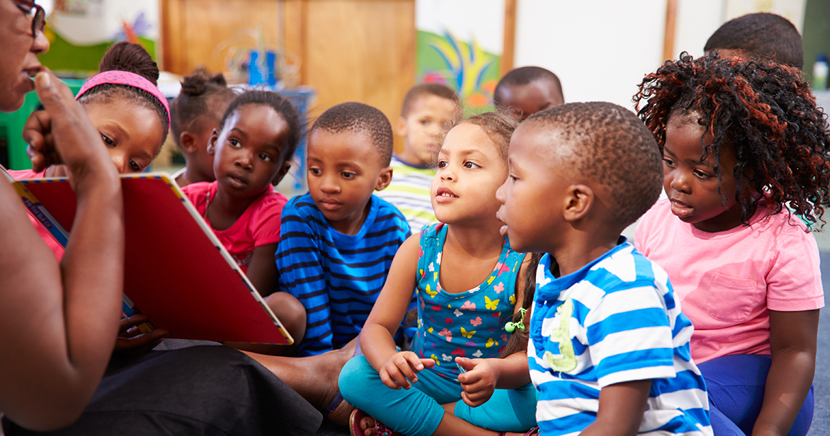 a teacher showing a book to little kids