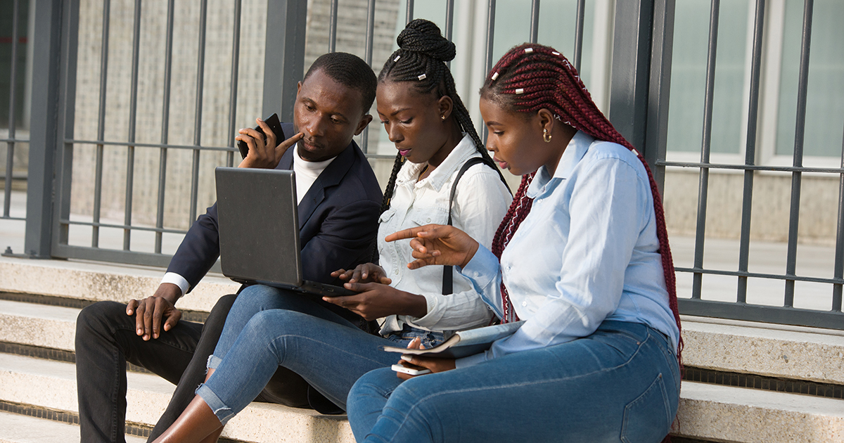 Group of young adults sitting on steps looking at a tablet