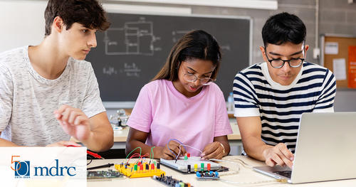 Three high school students work on a circuit board together