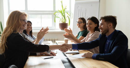 Smiling colleagues shaking hands across a conference table