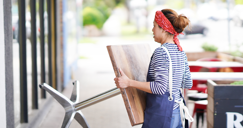 Female restaurant employee moving a table outside