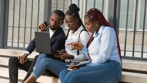 Group of young adults sitting on steps looking at a tablet