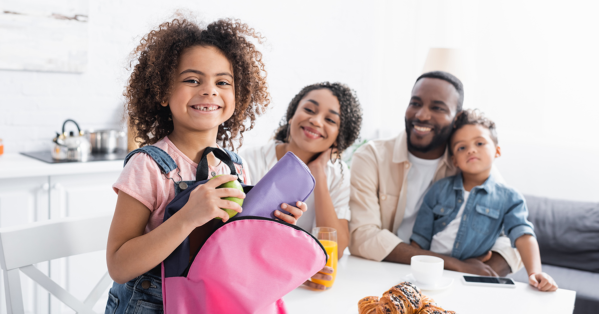 a kid is packing a bag for school after breakfast with her family