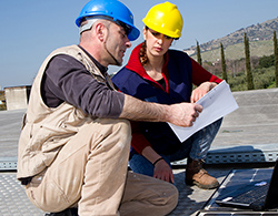 Two construction workers look at specs