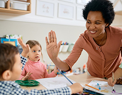 Teacher high-fives a pre-K student