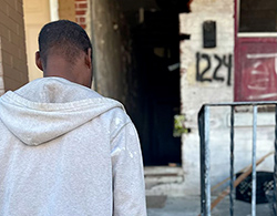 Black man walking toward a dilapidated building