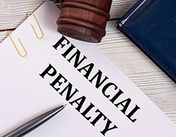 Paper with the words FINANCIAL PENALTY surrounded by a gavel and a pen