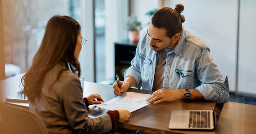 A social worker conducts a supportive housing eligibility screening in an office with a man wearing a denim shirt