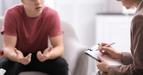 Young man speaking with a counselor as she takes notes